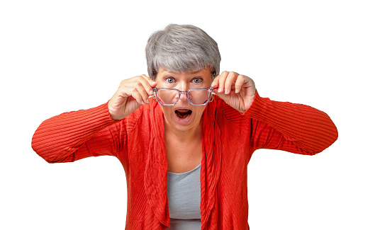 Senior woman looking into reading glasses and shouts in surprise isolated on white background