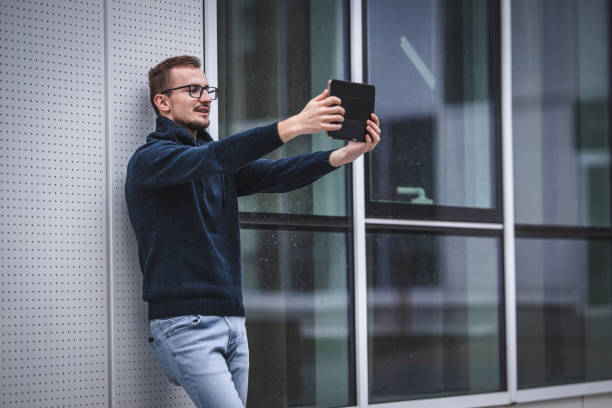 istock Young man video chatting using digital tablet on airport 1344851909