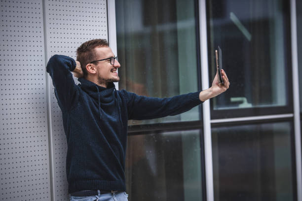 istock Young man video chatting using digital tablet on airport 1344851917