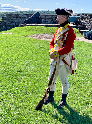 Niagara on the Lake, Canada – June 20, 2019: Actor dressed like an 18th century soldier is firing a musket. Location is Fort George a historic military structure at Niagara