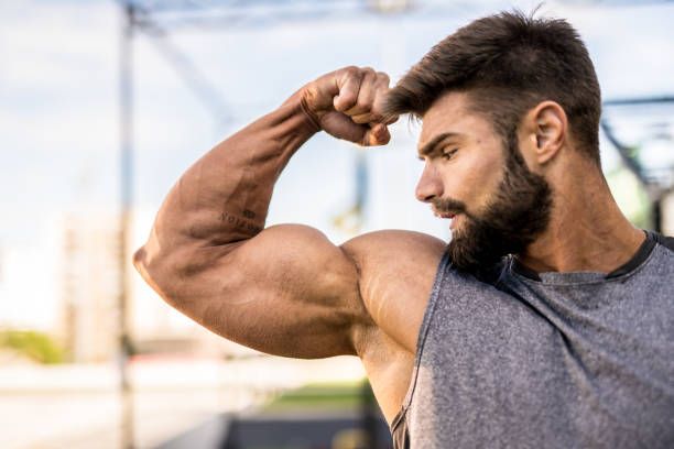 A black bodybuilder is intensely exercising indoors, developing their muscular build and strength. Sweat dripping off their chest muscles shows the dedication to a healthy lifestyle and sports training.