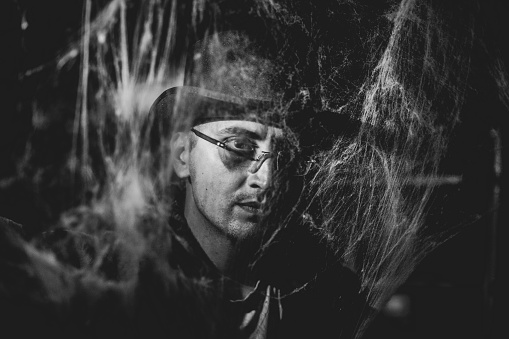 Black and white Creepy young man portrait behind spider web for Halloween