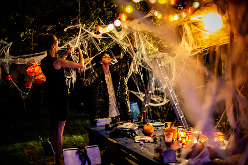 Friends arranging Halloween party decorations in the backyard