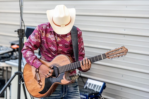 Teenage hispanic boy wearing a cowboy hat playing guitar