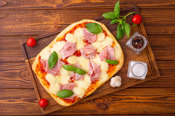 istock Traditional italian pizza with ham mozzarella and  basil 1344856972