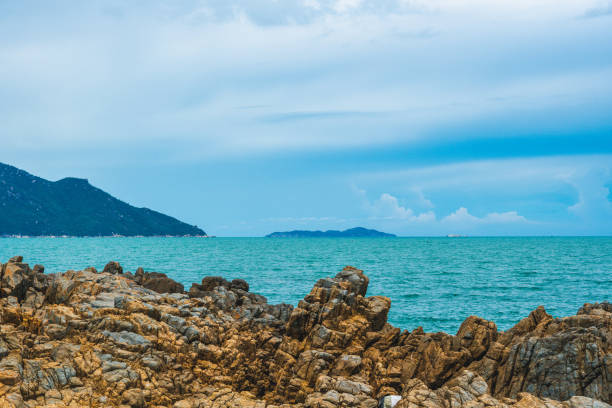 Beauty panorama vivid brown rock shabby cliff, skyline in pure blue lazure sea, cumulus cloud sky, mountain island background, empty sea background. Tourism recreation after pandemic summer vacation Beauty panorama vivid brown rock shabby cliff, skyline in pure blue lazure sea, cumulus cloud sky, mountain island background, empty sea background. Tourism recreation after pandemic summer vacation. slate ridge stock pictures, royalty-free photos & images