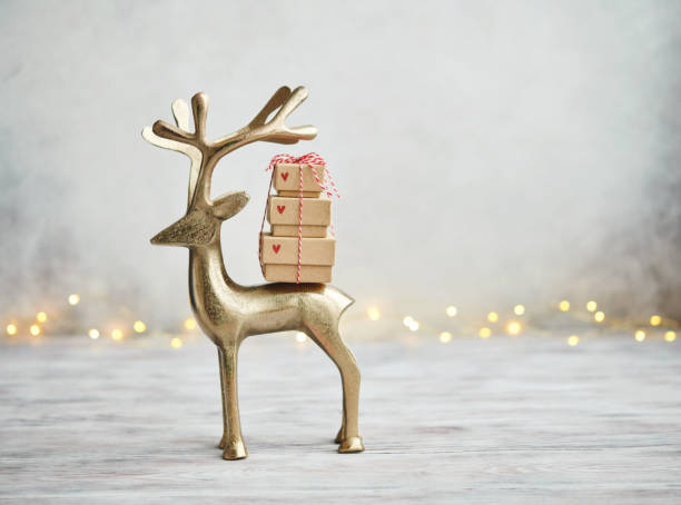 simpatico cervo d'oro che trasporta una pila di regali su sfondo grigio chiaro per natale - christmas stack gift carrying foto e immagini stock