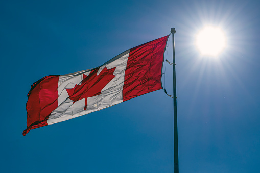 Canada flag waving on a blue sky in the Sunrise