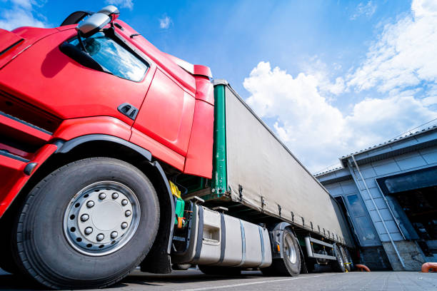 istock Large trucks near warehouse against blue sky background 1344859997