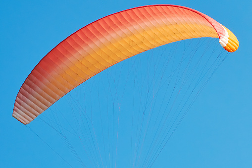 Colorful paraglide parachute in the blue sky. Extreme sport and leisure activity
