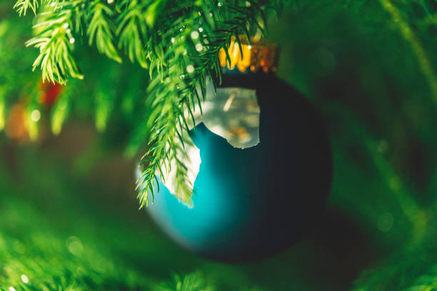 White Christmas bauble with hearts and a red star, in the foreground, and the bokeh of a lit garland in the background. (christmas ball)
