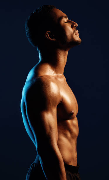 студийный снимок подтянутого молодого человека, позирующего на черном фоне - abdomen abdominal muscle muscular build beautiful стоковые фото и изображения