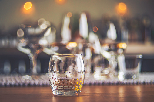 Collection of Empty Wine and Spirit Glasses in Dining Room with Defocused Bar in Background