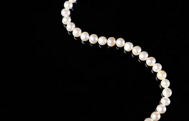 istock White pearls necklace on black background. 1344865315
