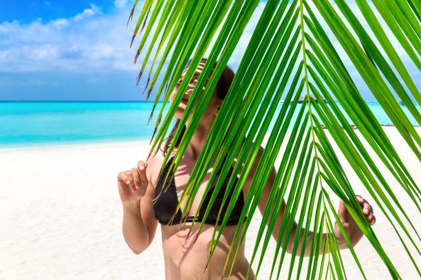 istock Woman hiding behind palm leaves 1344867370