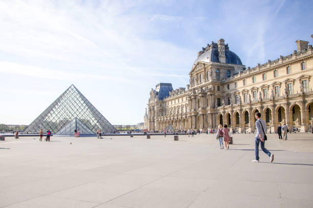 beaucoup de touristes se promènent sur la place de la pyramide du musée du louvre à paris, france - ile de france photos photos et images de collection