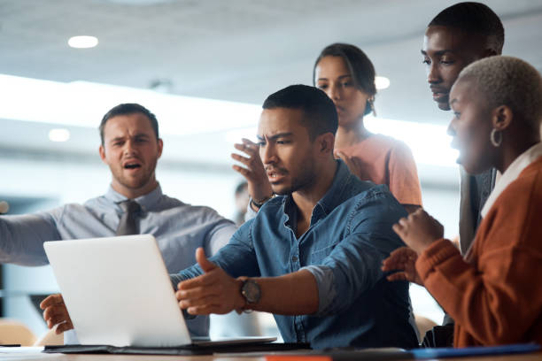 photo d’un jeune homme d’affaires brisant un ordinateur portable lors d’une réunion d’équipe dans un bureau moderne - violence black men women photos et images de collection