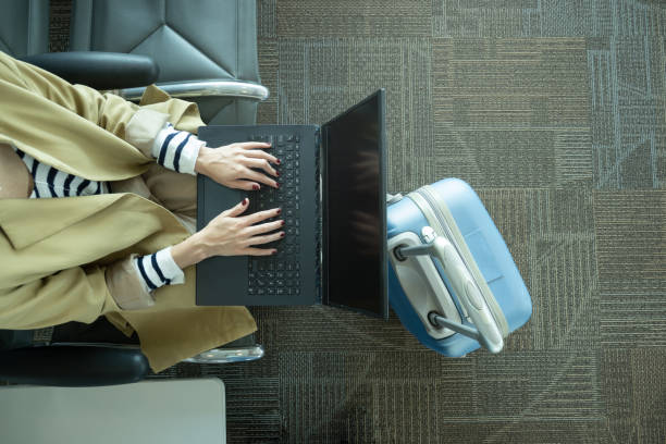 Close-up shot of unrecognizable woman working with laptop at airport next to luggage Top view of unrecognizable woman working with laptop in airport next to luggage with copy space digital nomad stock pictures, royalty-free photos & images
