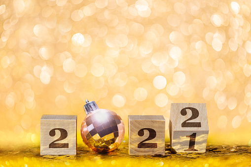 Christmas and New Year golden glittering background with number 2022 and pink Christmas ball with shiny and blurred backdrop