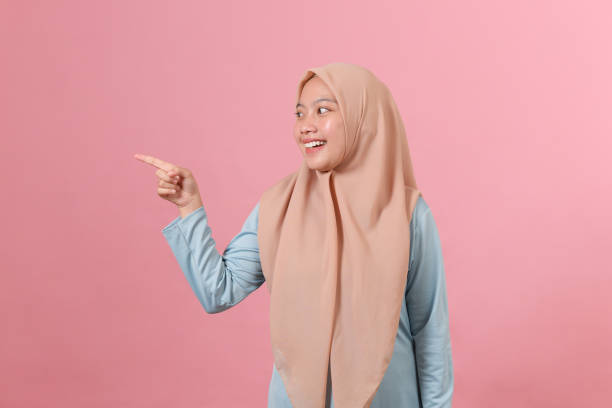 istock Young Asian muslim woman points a copy space 1344874506