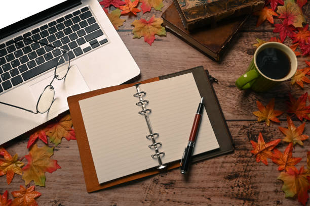 istock Notebook, laptop computer, coffee cup and autumn maple leaves on wooden background. 1344878943