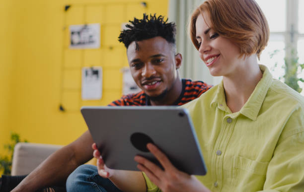 istock Young biracial couple using tablet, having fun indoors at home, checking social networks together. 1344883728