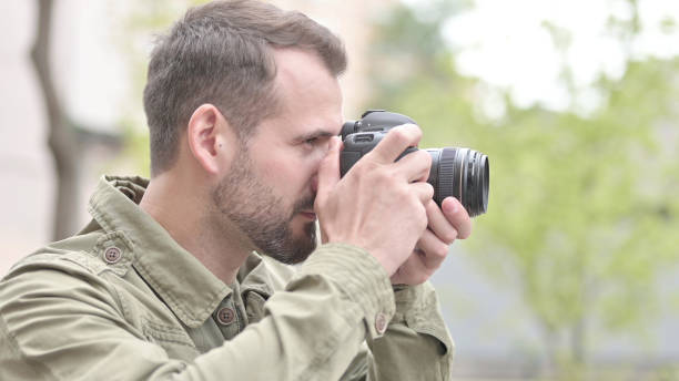 istock Handsome Man Clicking Pictures Outdoors on Camera 1344885893