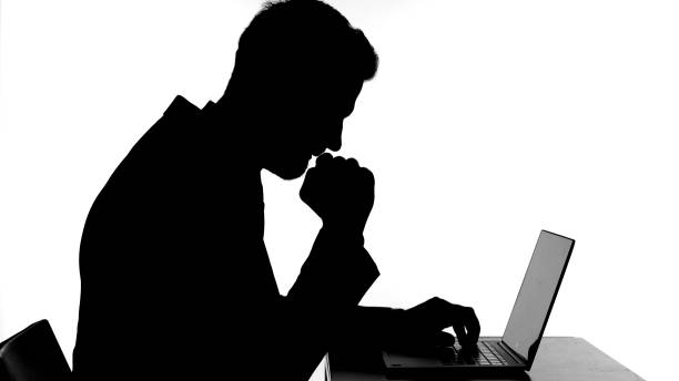 istock Silhouette of Sick Man Coughing While Working on Laptop 1344886133