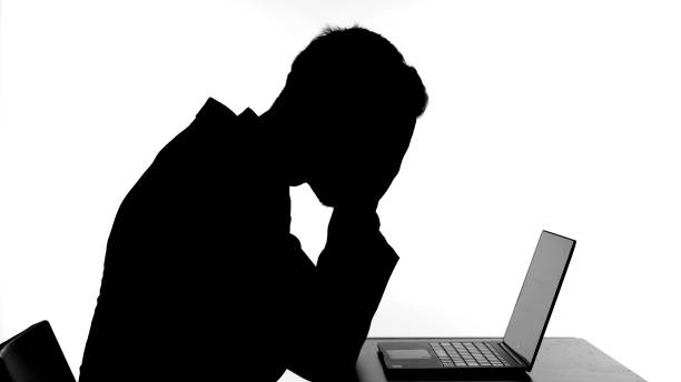 istock Silhouette of Upset Man Working on his Laptop 1344886238