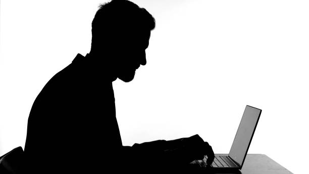 istock Silhouette of Young Man Working on Laptop 1344886270