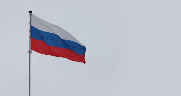 istock Russia flag on gray cloudy sky. 1344886304