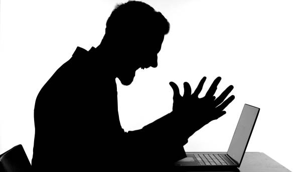 istock Silhouette of Angry Man Working on Laptop and getting Stressed 1344886311