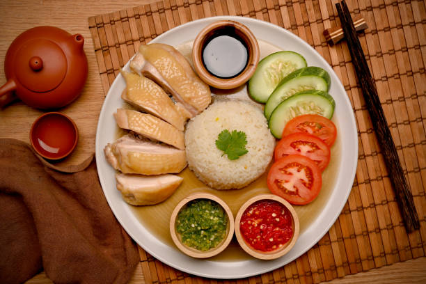 el arroz de pollo hainanés se sirve con salsa de chile, una guarnición de toboganes de tomate y pepino - isla de hainan fotografías e imágenes de stock