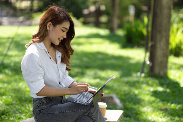 istock Side view of A beautiful woman working on a tablet while sitting on a stone bench 1344895011