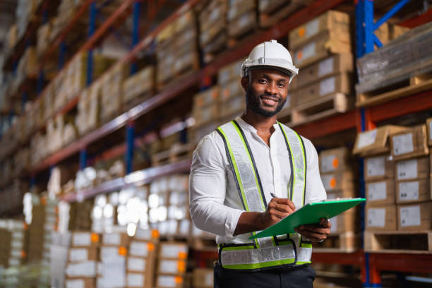 Portrait of an African warehouse manager holding a clipboard checking inventory in a large distribution center. stock photo