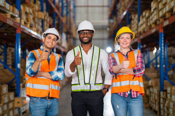 A small group of warehouse workers standing in a large distribution center stock photo