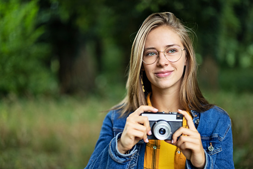 Smiling teenage girl holding a vintage camera. The girl is walking in the forest and taking photos.
Canon R5