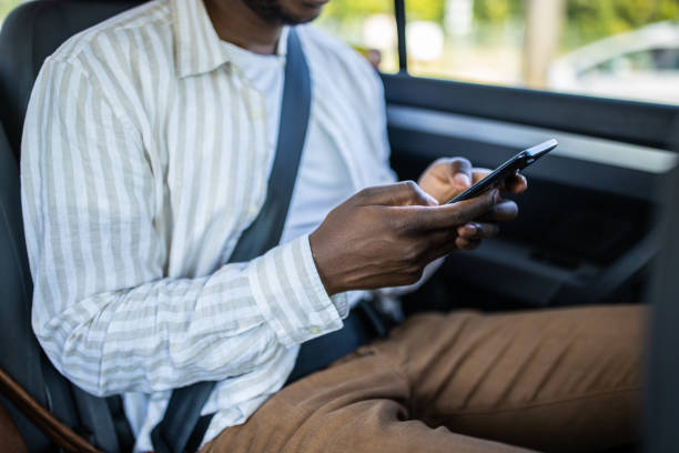 istock Young man sitting on back seat text messaging using smart phone while traveling by car 1344898557