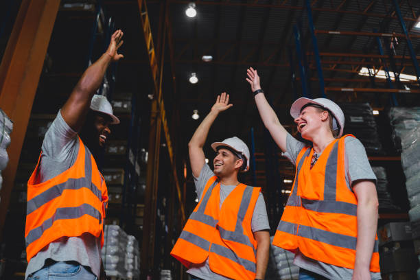 A Group of Diversity warehouse workers giving hand for high-five after success the project and celebrating together in a distribution center warehouse. stock photo