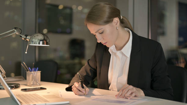 istock Ambitious Businesswoman doing Writing Documents at Night 1344902280