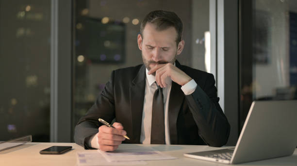 istock Young Businessman Thinking and writing Document at Night 1344902752