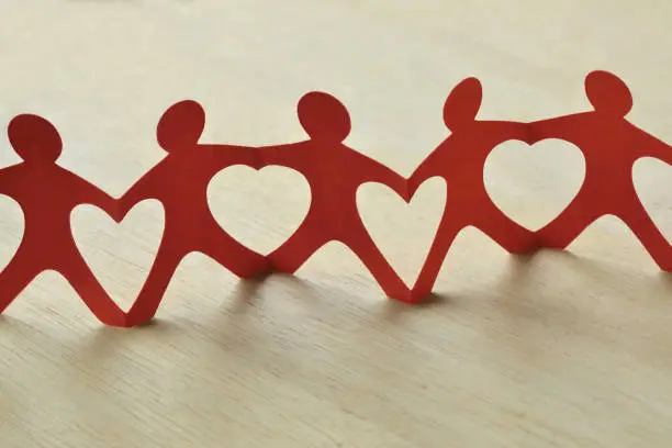 Photo of Paper people chain with hearts - Teamwork and love concept