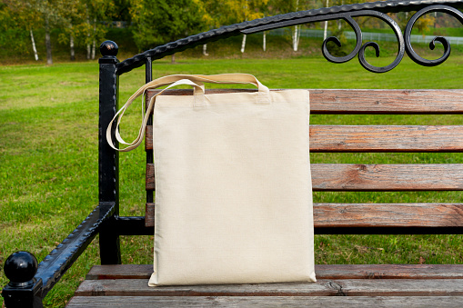 Canvas tote bag on the steel patio bench mockup. Rustic linen shopper bag mock up for branding presentation