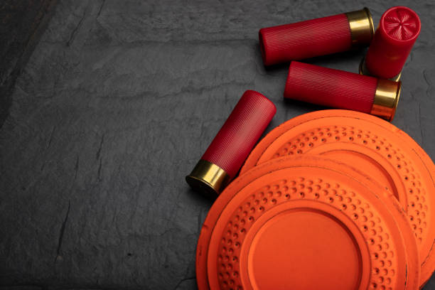 istock Clay shooting target with shotgun shell on black slate background , Shotgun game 1344904841