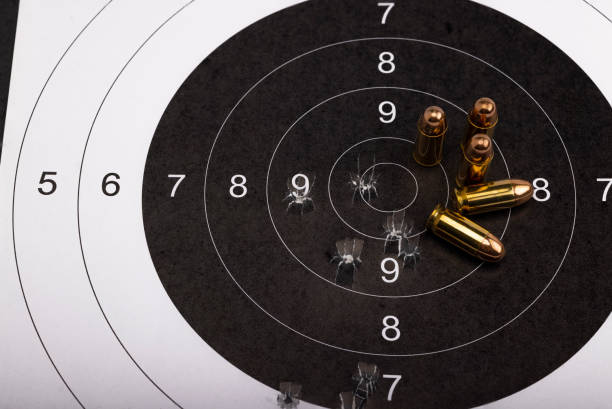 .45 balles d’armes à feu sur fond de cible en papier bull eye - gun rounds photos et images de collection
