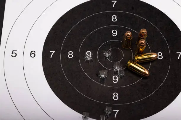 Photo of .45 Gun bullets on bull eye paper target background