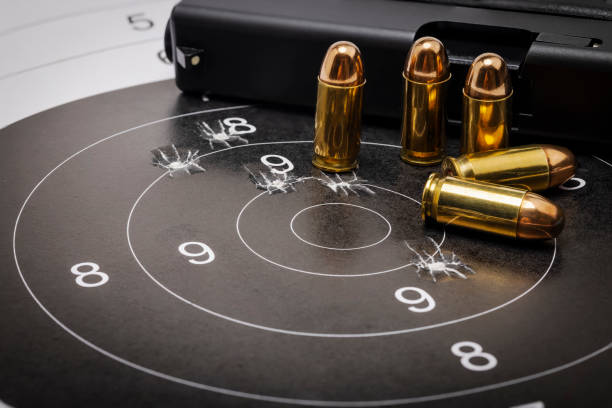 balas de pistola en el objetivo de papel ojo de buey y fondo de pistola semiautomática - target shooting fotografías e imágenes de stock
