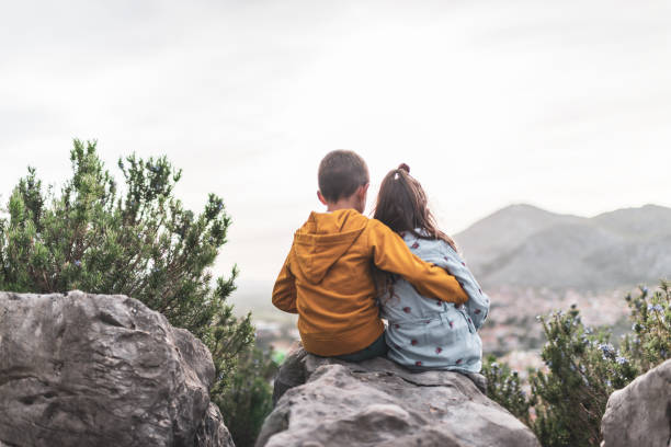istock Young boy and girl enjoying mountains at sunset 1344906249