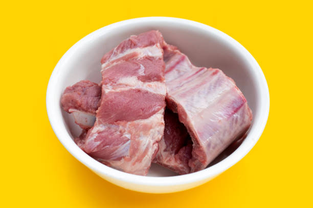 istock Raw pork ribs in white bowl on yellow background. 1344908265