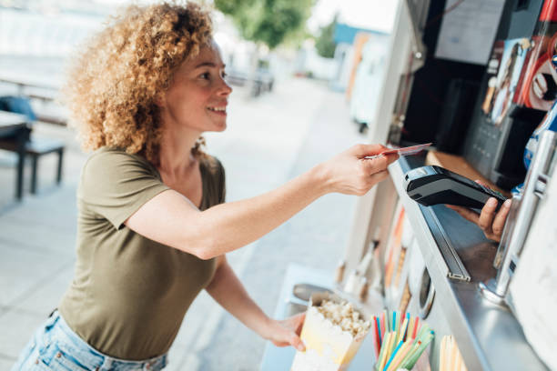istock Happy young woman paying for popcorn 1344908896